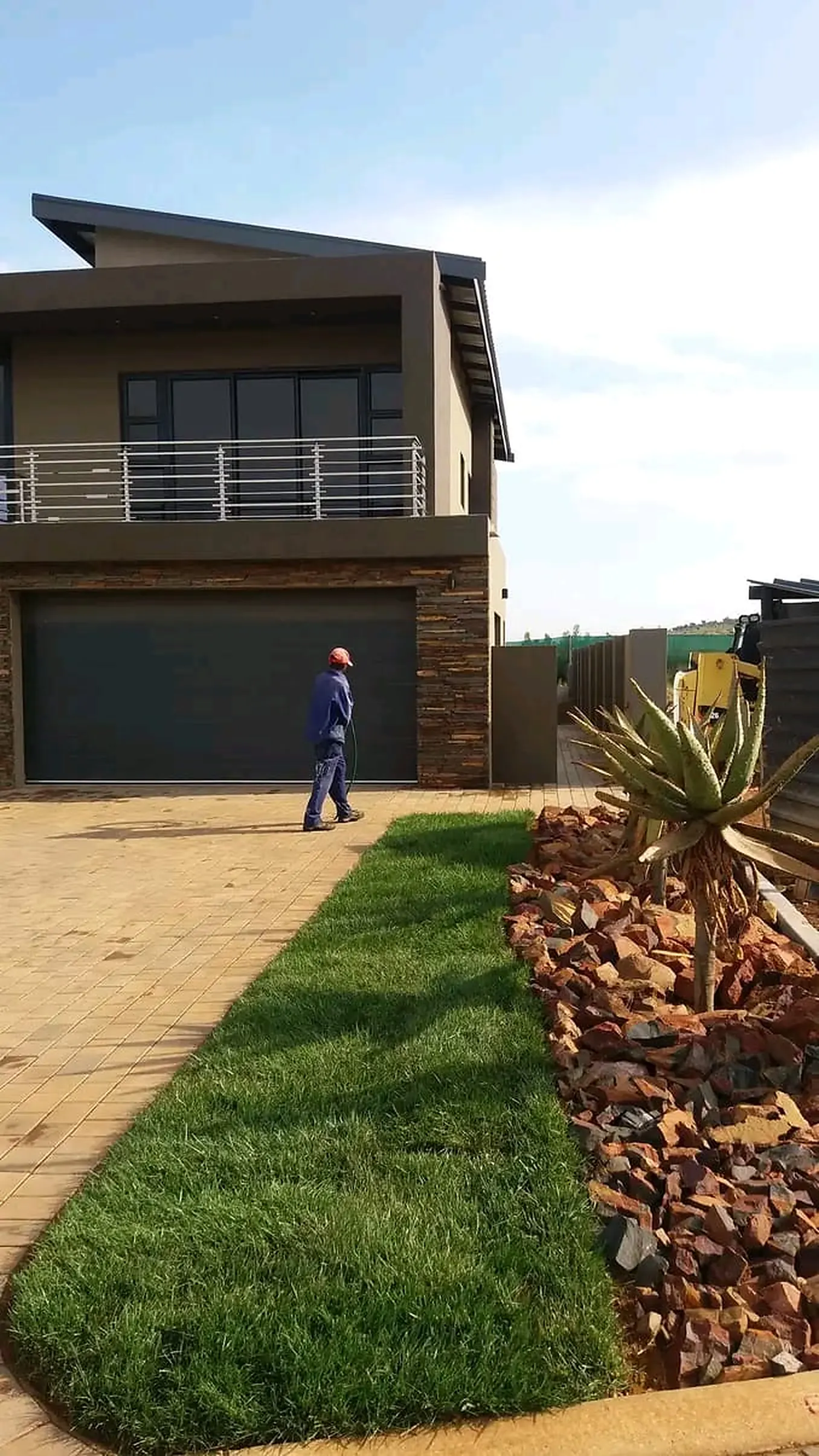 A landscaped driveway garden with lawn and an aloe rock bed
